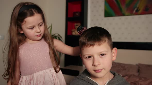 Sister Makes a Hairstyle to Brother Combs Her Hair with Comb at Home Bedroom