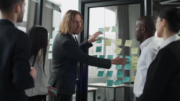 Business Meeting International Management Team at Work Team Is Standing Next To a Glass Board with