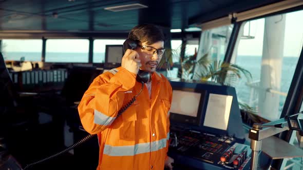 Filipino Deck Officer on Bridge of Vessel or Ship. He Is Speaking on GMDSS VHF Radio