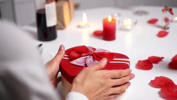 Young Woman Opens A Gift Box And Claps Her Hands Happily. Women's Hands Hold Gift Box A Heart