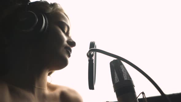 Beautiful sexy young woman singing. Female vocal. Professional recording studio. Close-up face.