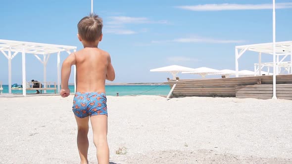 Happy Little Boy Runs Along the Seashore on the Beach.