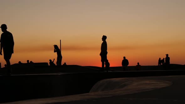 Silhouette of Young Jumping Skateboarder Riding Longboard, Summer Sunset Background. Venice Ocean