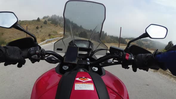 POV Biker on Motorcycle Rides on High Mountain Pass in Cloudy Weather with Fog