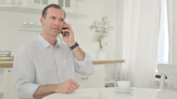 Middle Aged Man Talking on Smartphone at Home