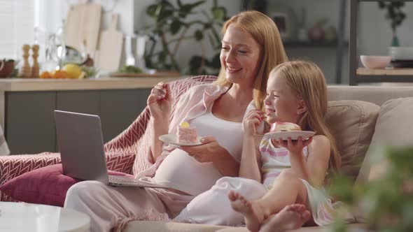 Pregnant Woman Watching Moving on Laptop with Daughter