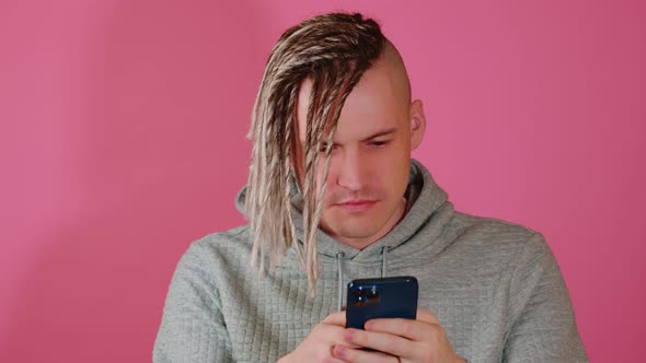 A Young Man with Dreadlocks Uses a Smartphone in the Studio