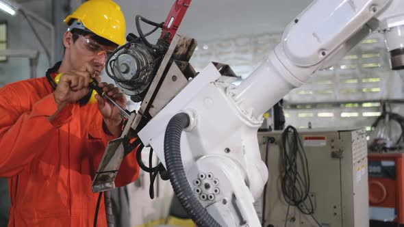 Factory worker man use tool to fix and maintenance part of robotic machine in workplace