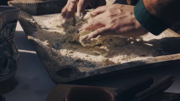 hands mixing flour and water together to prepare the dough