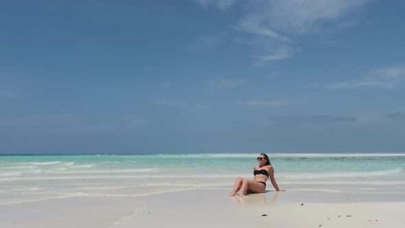 Young Woman in Bikini Tans on an Empty Paradise Beach on Island in Ocean Mnemba