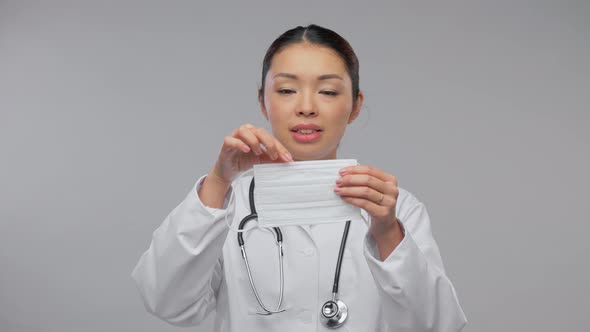 Happy Asian Female Doctor Showing Medical Mask