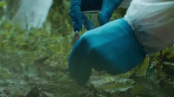 Process of Taking Soil Analysis Using Flask and Little Shovel Wearing Protective Suit and Gloves