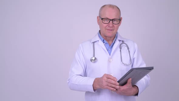 Happy Senior Man Doctor Using Digital Tablet and Showing Something