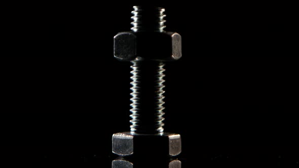 Nut To Middle Wound on Bolt Rotates on Black Background