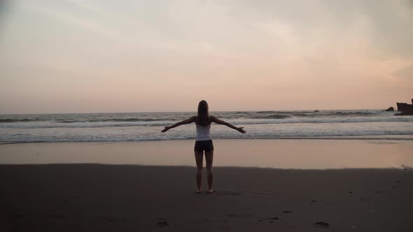 Woman Meditating on Ocean Coastline at Scenic Sunset