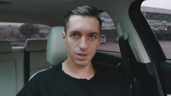 Portrait of a Young Smiling Man Who Is Sitting in the Car Taking Off His Sunglasses. Handsome Male