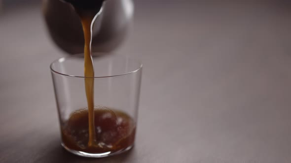 Slow Motion Coffee Pour Into Tumbler Glass on Walnut Table
