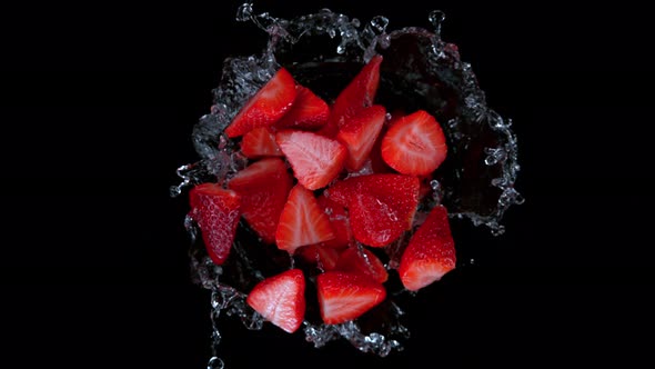 Super Slow Motion Shot of Rotating Exploded Strawberries with Splashing Water on Black at 1000Fps