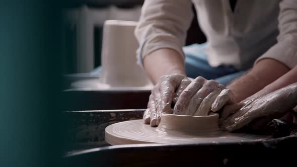 Close Up of Hands of Man Helping Kid with Clay Pottery Wheel, Teaching Concept