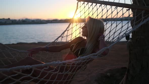 Travel and Vacation Concept  Woman Relaxing on Hammock on the Beach at Sunset