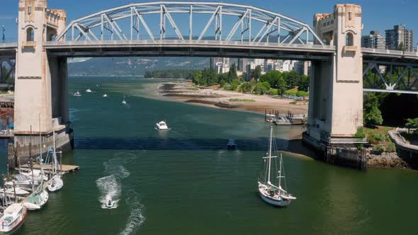 Aerial View Of Sailboats Passing Under Burrard Street Bridge Over False Creek With Sunset Beach In B