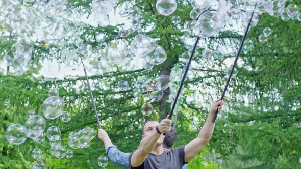 Men Performing Soap Bubbles Tricks in Park