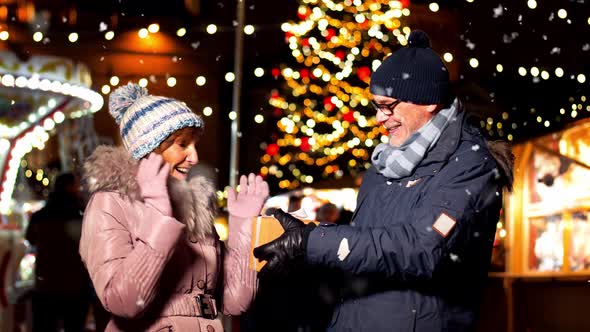 Happy Senior Couple with Gift at Christmas Market
