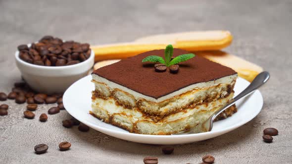 Portion of Traditional Italian Tiramisu dessert and coffee beans on grey concrete background