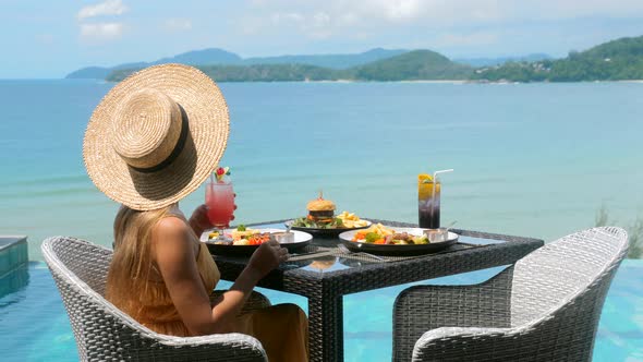 Travel Woman with Straw Hat Drinking Cocktail on Lunch with Sea View