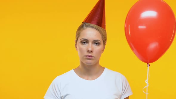 Upset Lady in Birthday Hat Holding Balloon and Blowing in Party Horn, Loneliness