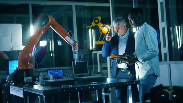 IT Laboratory with Two Male Engineers Researching a Robotic Device