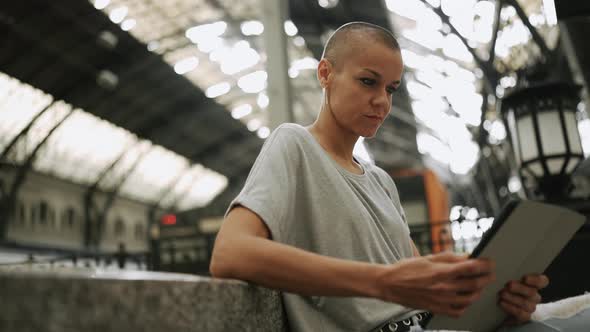 Pensive bald woman wearing t-shirt reading e-book