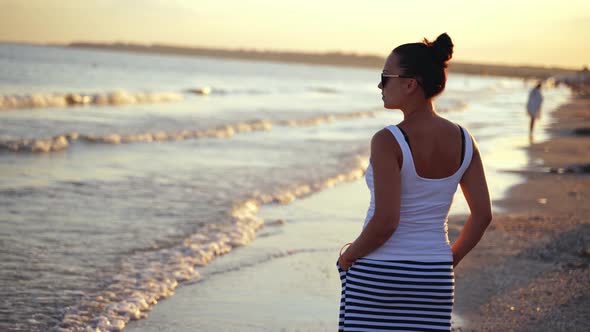 Portrait of woman looking at sea. Rear view of young woman looking at sea