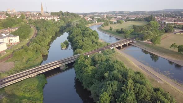Aerial fly over of railway crossing River Exe in Exeter, UK at golden hour