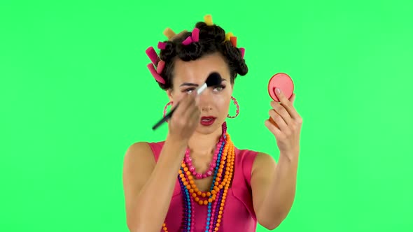 Girl with Curlers on Her Head in a Pink Dress Looking in Red Mirror and Powdered Her Nose with Big