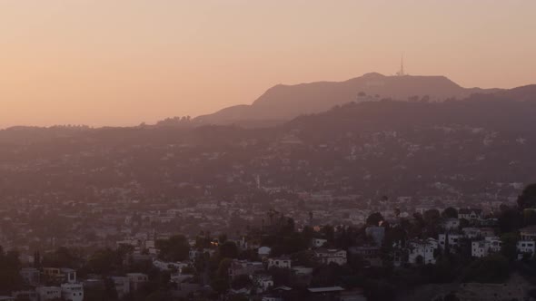 Aerial of buildings in city and mountains at a distance at sunset