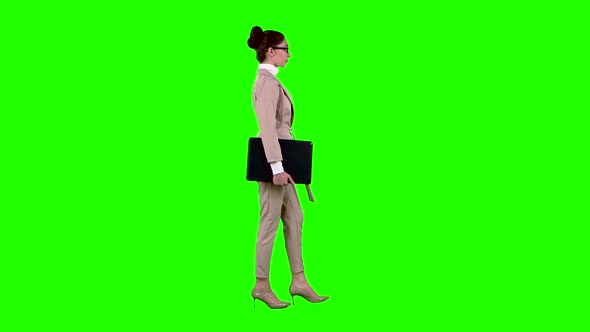 Girl Is Going To a Meeting with a Laptop in Her Hands. Green Screen. Side View. Slow Motion