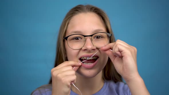 Girl with Braces Brushing Your Teeth with Dental Floss. A Girl with Colored Braces on Her Teeth