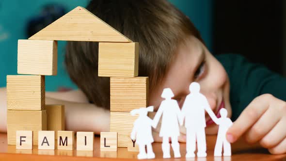 Caucasian boy 7 years old at home playing at the table in a family cut out of cardboard. The child d