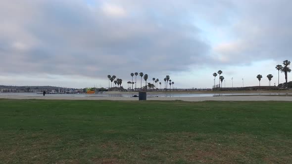 Tracking shot of a man jogging on on grass near a bay