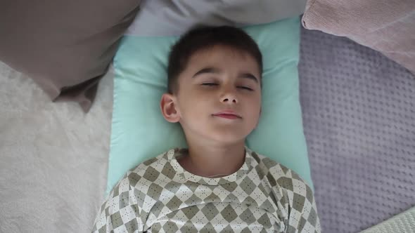 Little Boy Wakes Up Lying on a Bed with Pillows