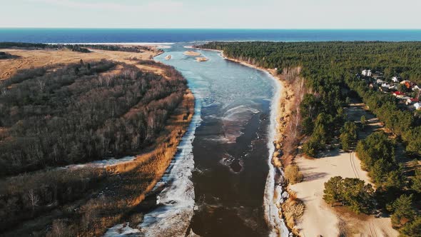 Flight Up Spring Aerial View Over River Joining Baltic Sea with Melting Ice and Snow