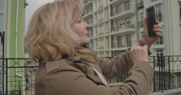 Close-up of Mature Caucasian Woman Photographing Sights in Foreign City. Happy Female Retiree