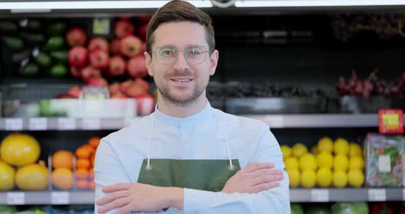 Close Up Portrait of Happy Man Worker in Glasses Wearing Apron Standing in Supermarket and Looking