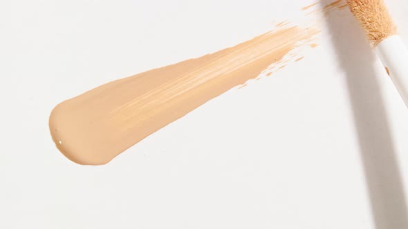 Macro Shot and Slow Motion of a Brush Applicator Smear Concealer Isolated on White Background