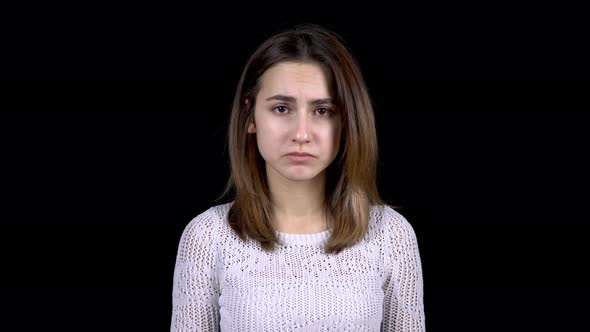 A Young Woman Shows Emotions of Sadness on Her Face. The Woman Is Sad on a Black Background.