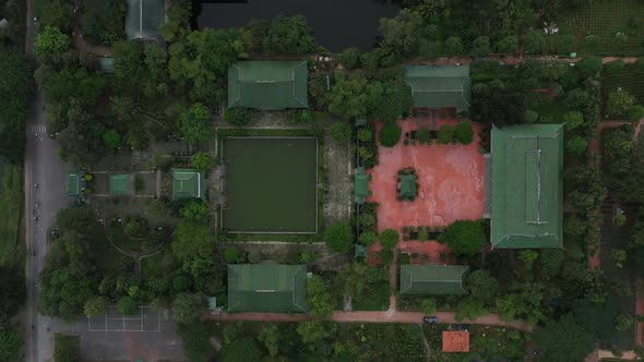 aerial top down tracking shot of ancient Buddhist temple, gardens and street with traffic in south V