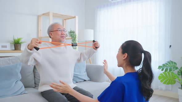 Asian older aged man using dumbbells doing physiotherapist with support from nurse.