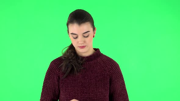 Upset Girl Guilty Lowers Her Eyes on a Green Screen in the Studio.