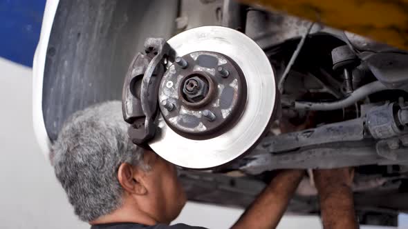 Old Grizzled Mexican mechanic Calibrating the brake disc of a car recently rectified In Tulum Mexico